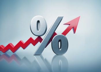 Percentage sign standing on reflective surface with red arrow moving up on defocused  background. Horizontal composition with copy space.